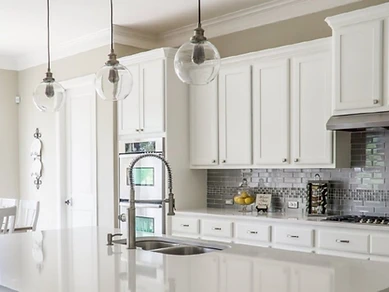 White shaker kitchen with subway tile backsplash, glass pendant lights and stainless steel sink, installed by Tabinets near Middleborough, MA