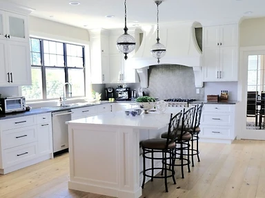 Bright modern white kitchen with central island, black bar stools and glass orb pendant lights, installed by Tabinets near Lakeville, MA