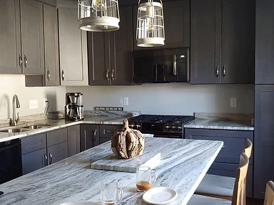 Dark charcoal shaker kitchen with marbled stone island countertop and industrial pendant lights, installed by Tabinets near Middleborough, MA