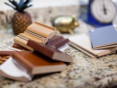 Kitchen material and wood trim samples in various stains and finishes on a granite countertop at the Tabinets showroom