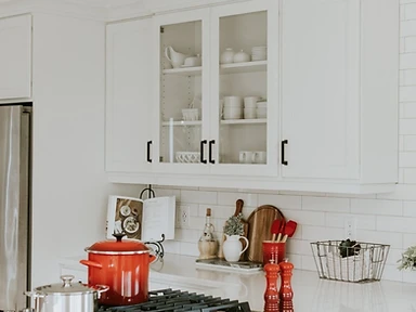 White shaker kitchen with subway tile backsplash and red enameled Dutch oven on a stainless steel gas range, installed by Tabinets near Middleborough, MA