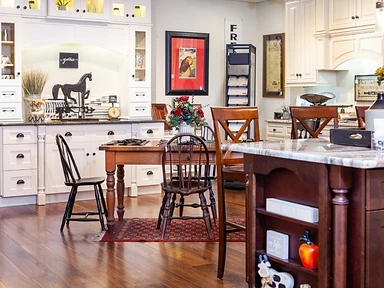 Kitchen showroom scene with white cabinetry, dining area and dark wood island with marble countertop, designed by Tabinets in Middleborough, MA
